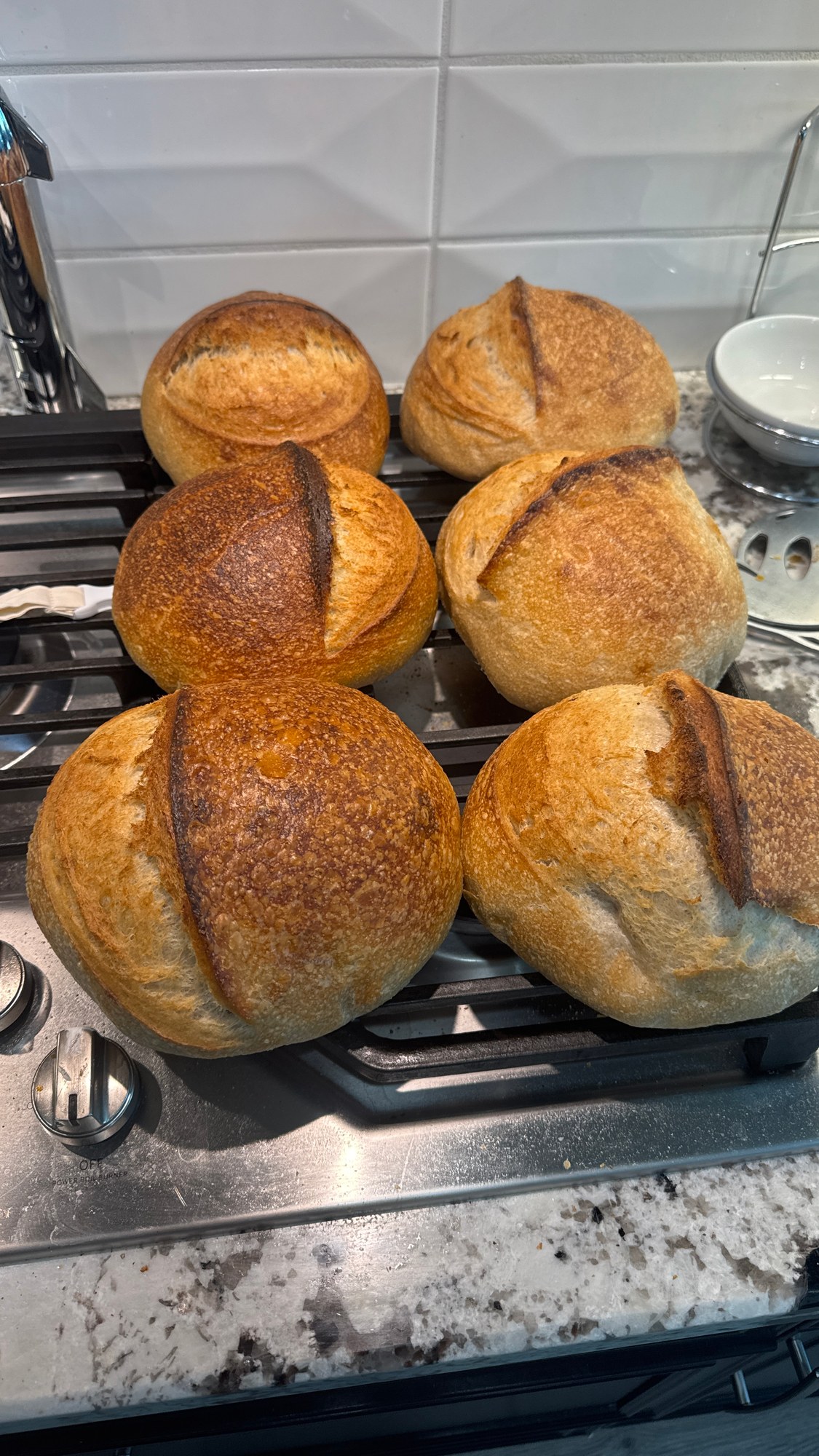 Golden round loaves with raised scores arranged on a stovetop