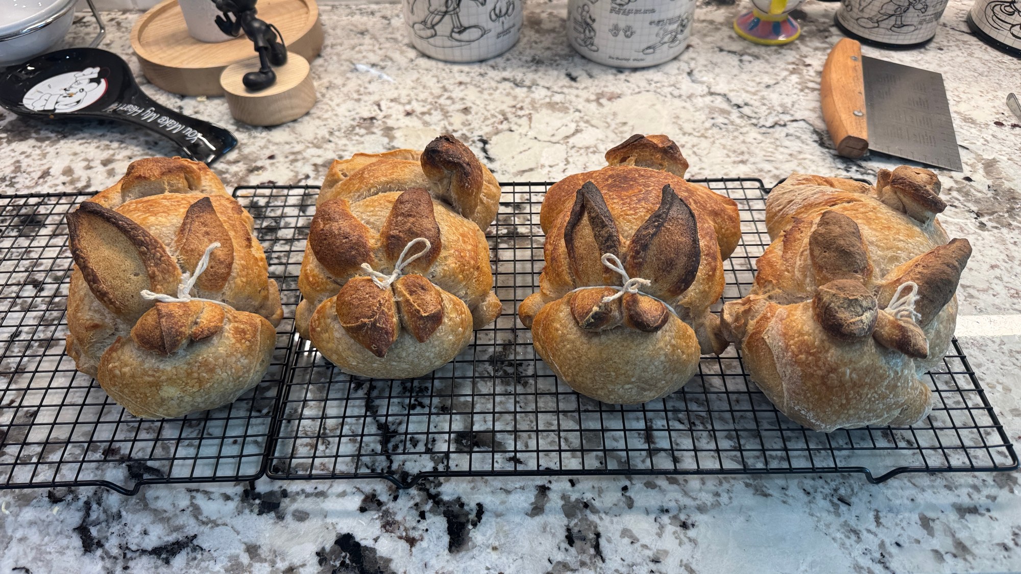 Four rabbit-shaped bread loaves with ears and tails on a cooling rack